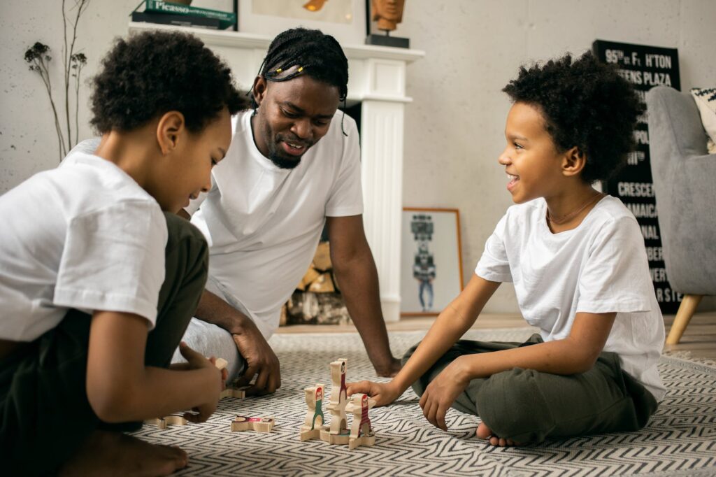 black man playing with children in living room
