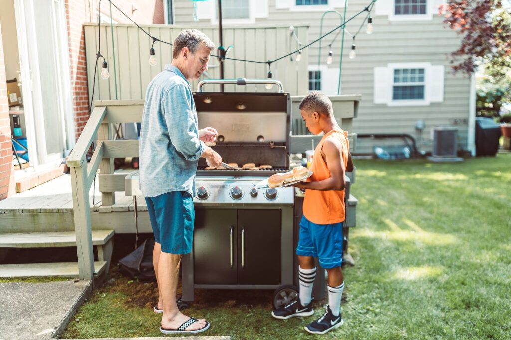 man and his adopted son cooking together in the backyard