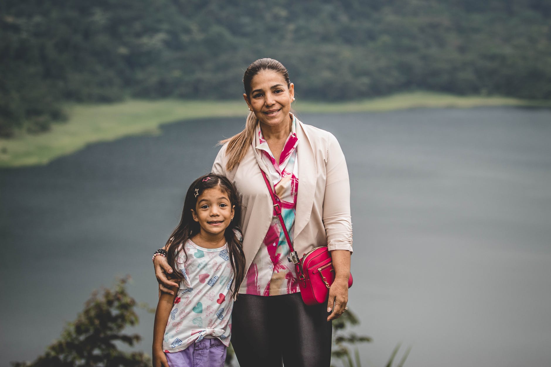 portrait of smiling mother and daughter by lake