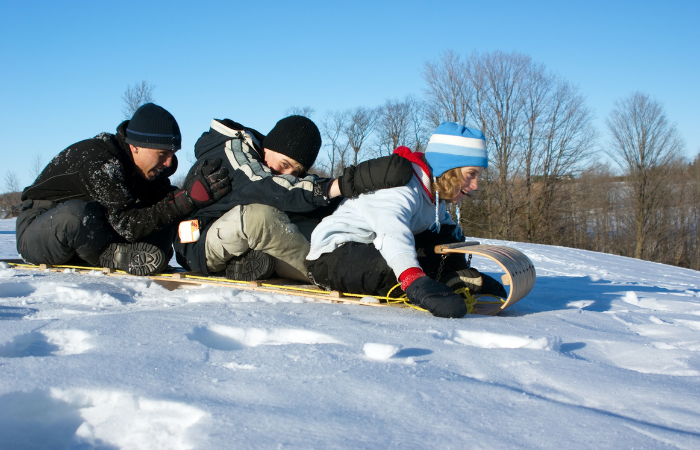 3 teens on a sled going down a hill. Winter date ideas for teen couples