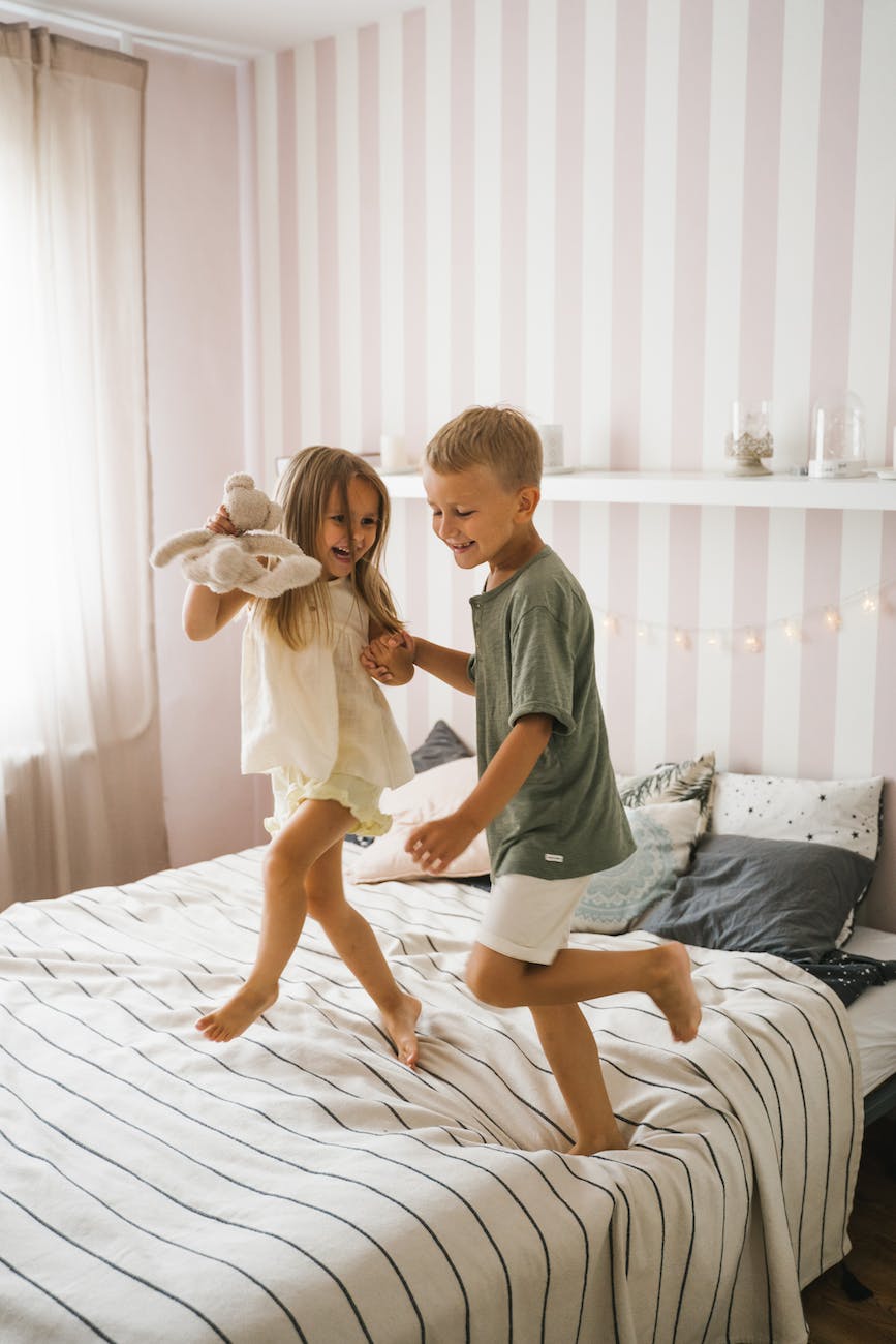 a happy boy and girl dancing on the bed get back into a routine after the holidays