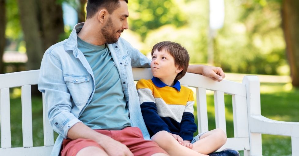 dad and son talking on a bench outside