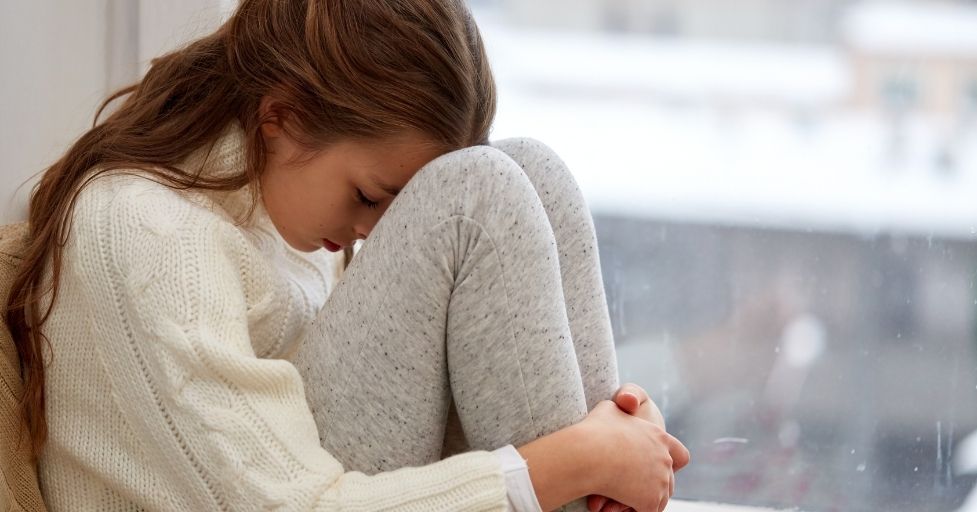 girl sitting on the floor with her head to her knees