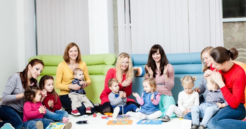 moms and children sitting on the floor and playing