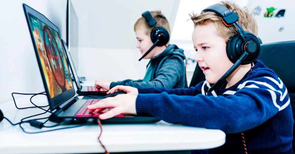 two boys playing video games on laptops