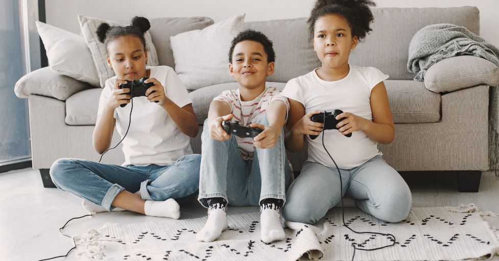 three kids sitting on the floor playing video games