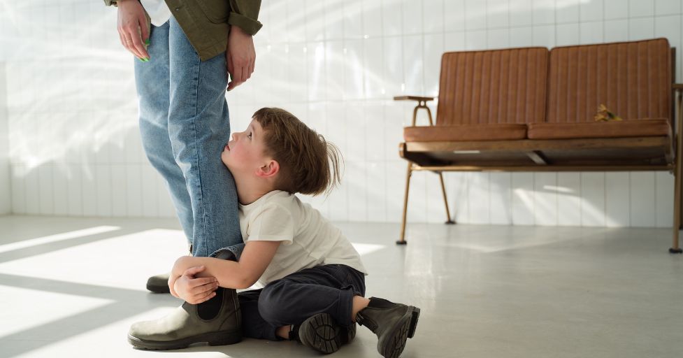 young boy holding on the leg of a man