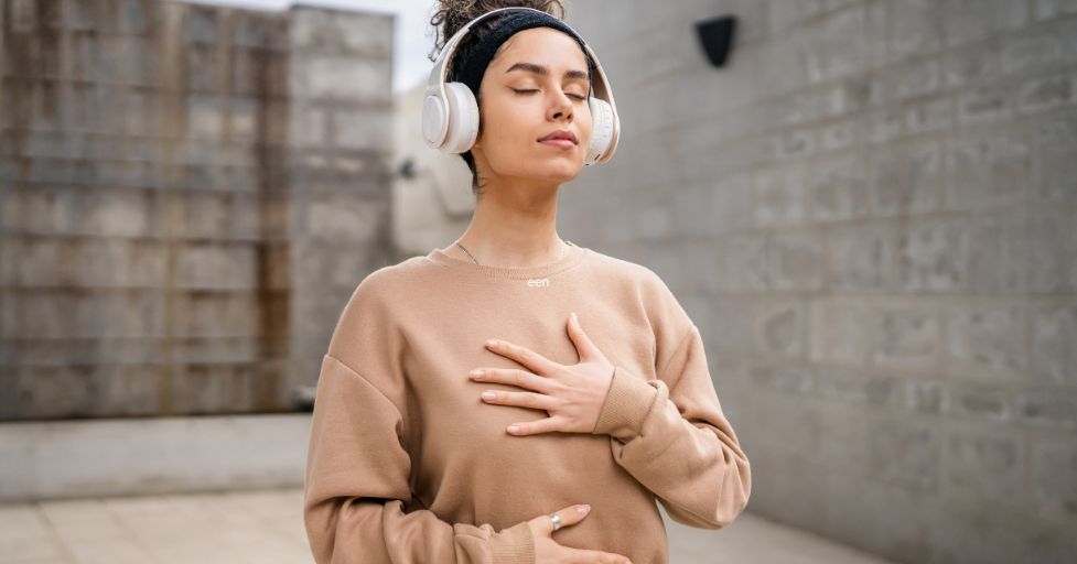 lady listening to something on headphones holding her chest 