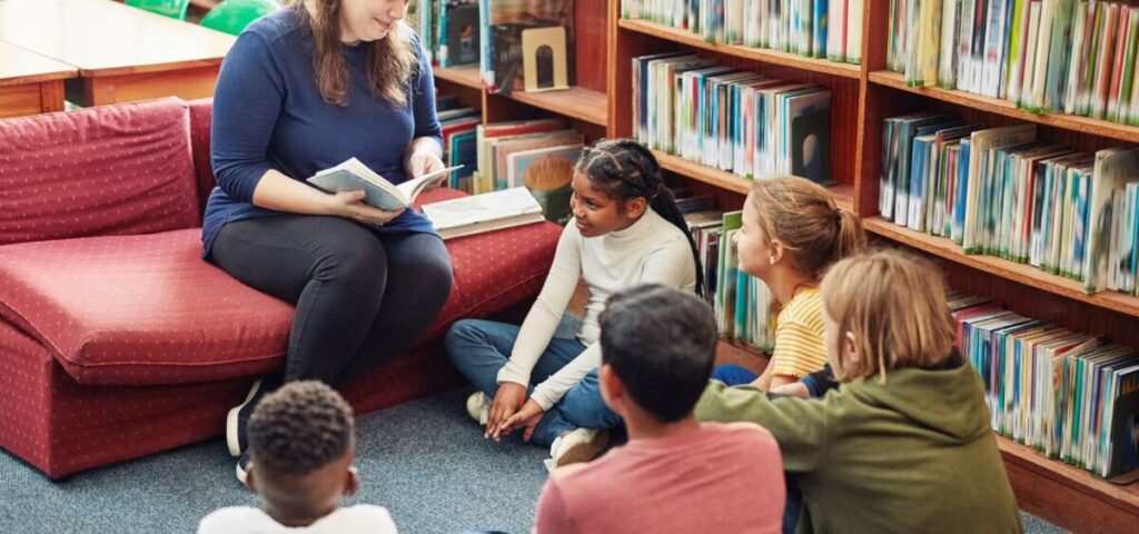 teacher reading book to kids in a library