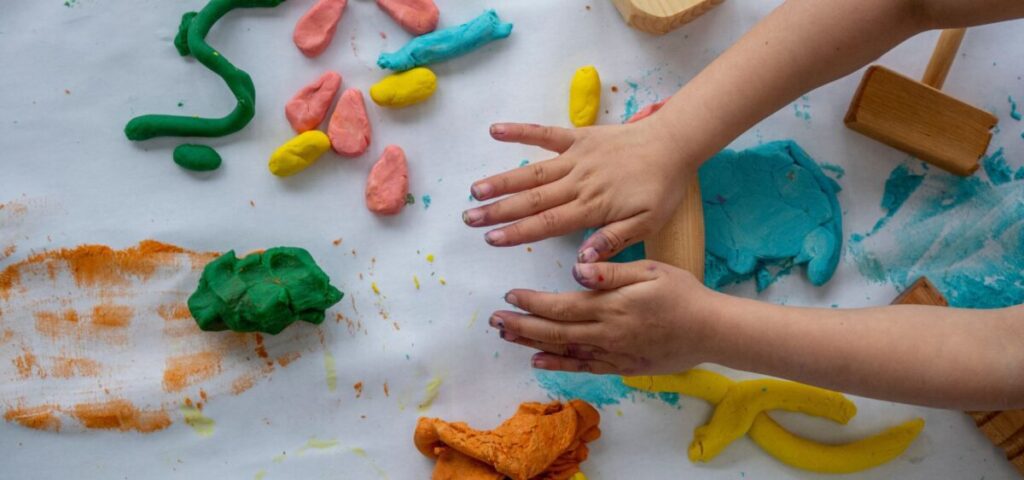 person hands playing with play dough