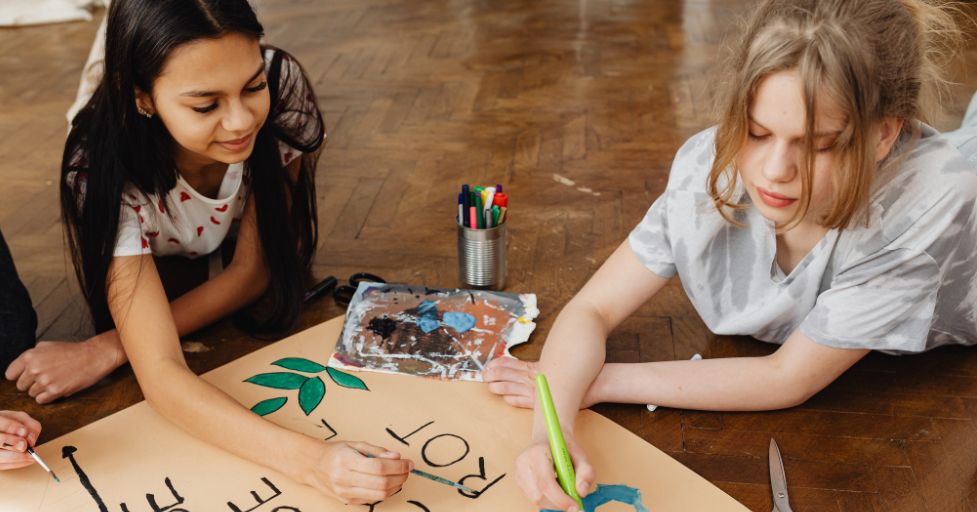 two girls on the floor painting a poster mindfulness quotes for kids