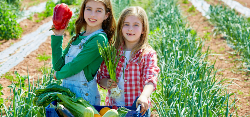 budget travel with children - two girls holding peppers and onion.