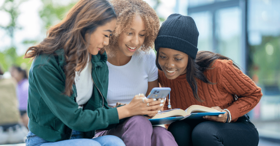 3 young adult women looking at a cell phone Social Media Impact on Teen Relationships