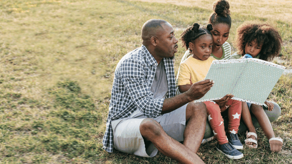August Bucket List for Families family sitting on the grass reading a book