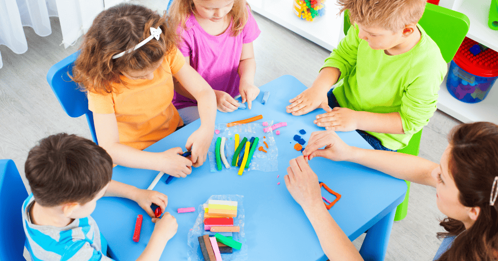 morning routine kindergarten young children in a classroom sitting at a table platying with playdough